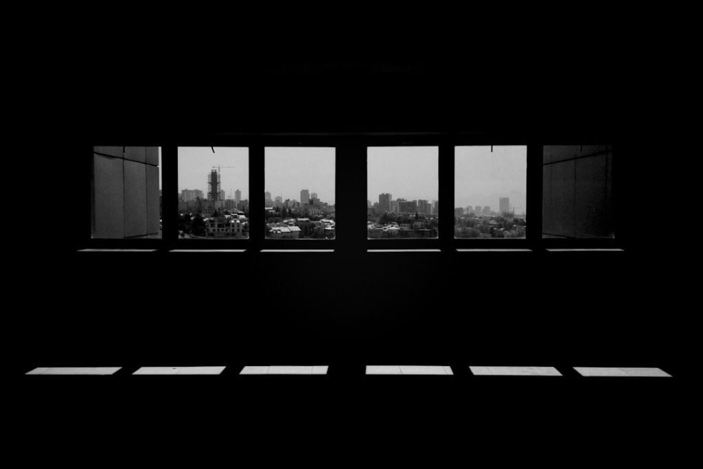 a-black-and-white-photo-of-a-window-with-a-view-of-a-city-obtuxltuu-e